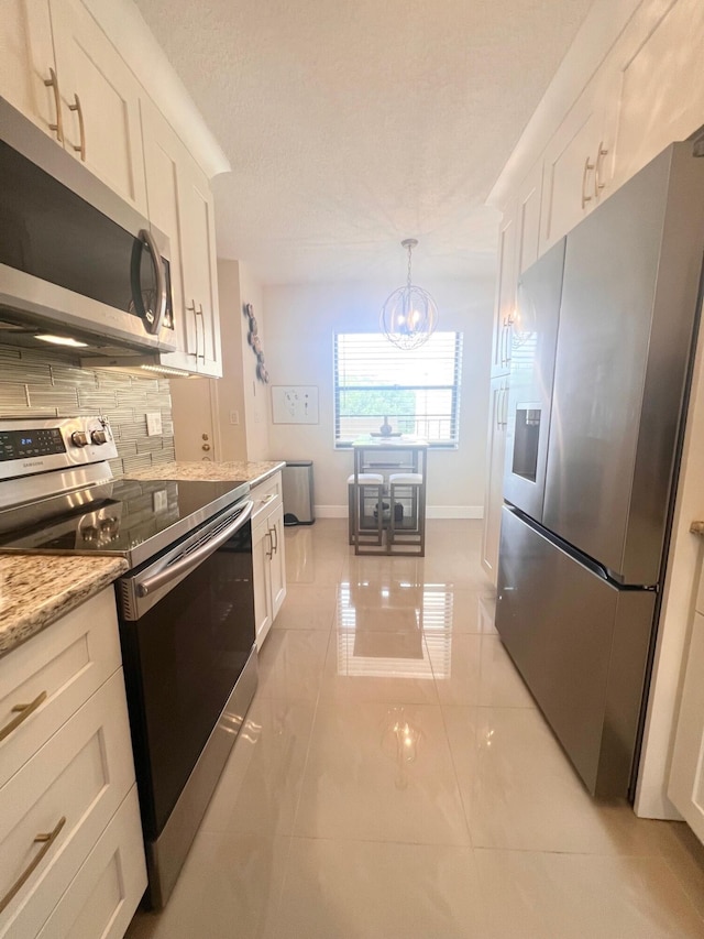 kitchen with stainless steel appliances, pendant lighting, and white cabinets