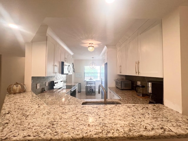 kitchen with tasteful backsplash, stainless steel electric range oven, white cabinets, and sink