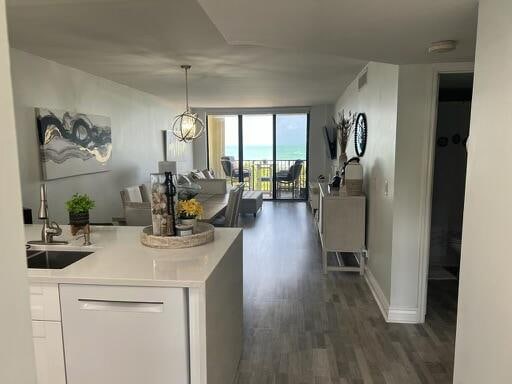 kitchen with white cabinetry, dark hardwood / wood-style flooring, white dishwasher, expansive windows, and sink