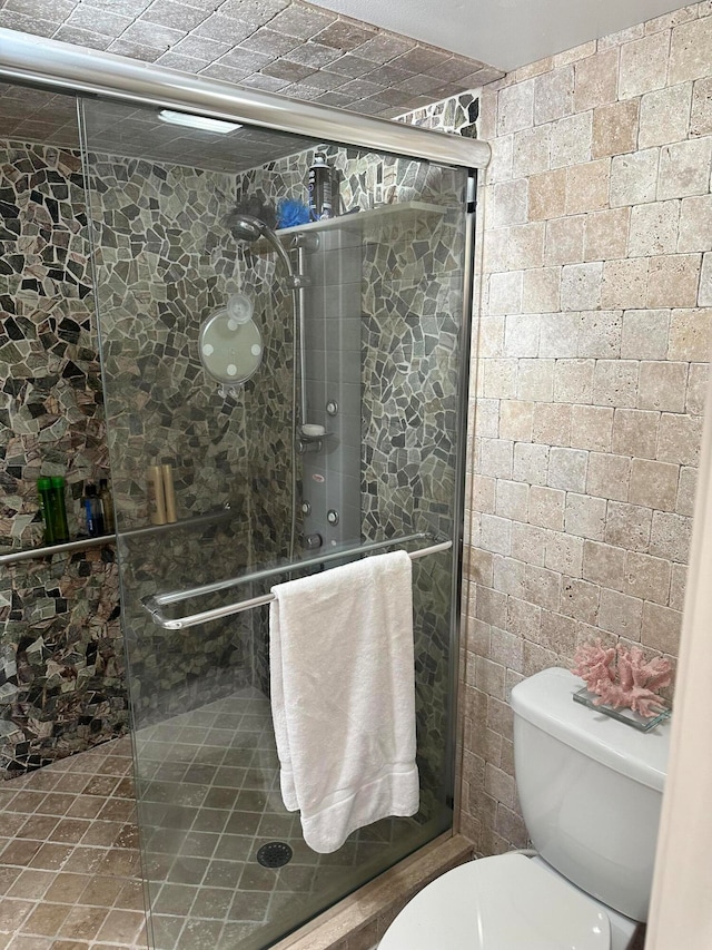 bathroom with a shower with shower door and toilet