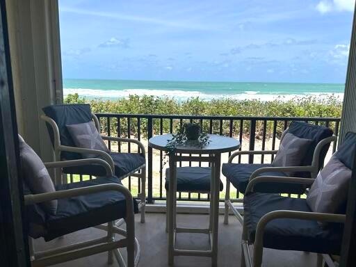 balcony featuring a view of the beach and a water view