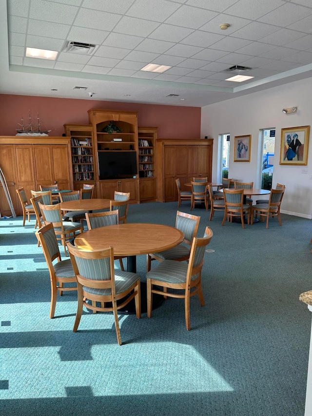 carpeted dining area with a drop ceiling