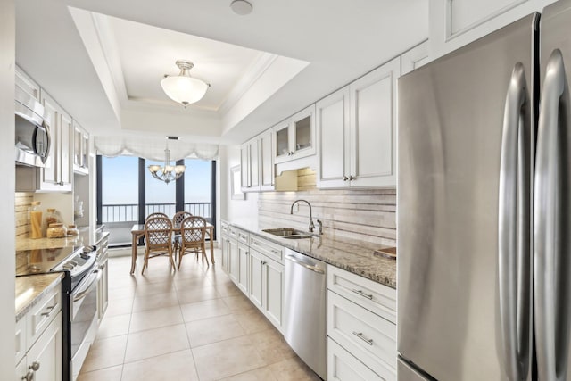 kitchen featuring tasteful backsplash, appliances with stainless steel finishes, sink, a tray ceiling, and white cabinetry