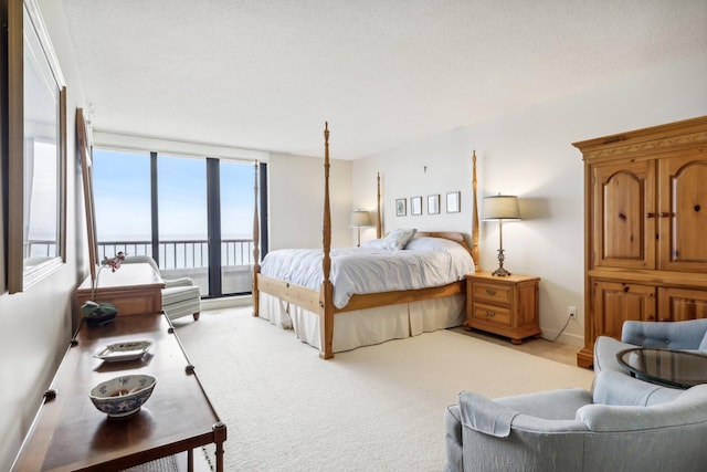 carpeted bedroom featuring access to exterior, a textured ceiling, and a water view