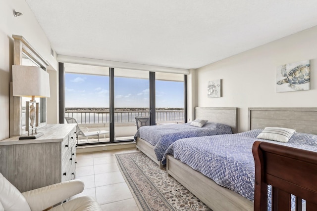 bedroom featuring access to outside, multiple windows, expansive windows, and light tile patterned floors