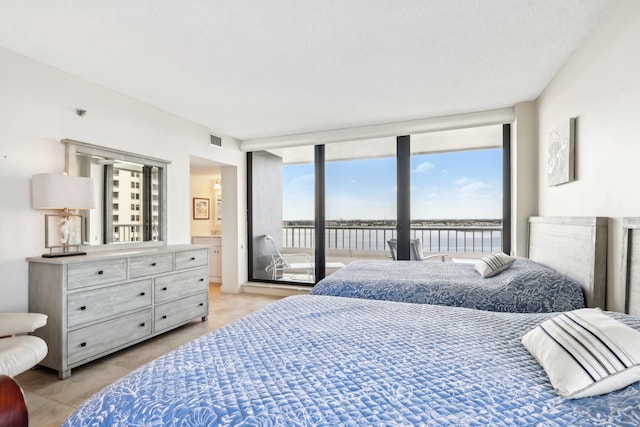 bedroom featuring connected bathroom, a water view, and access to outside