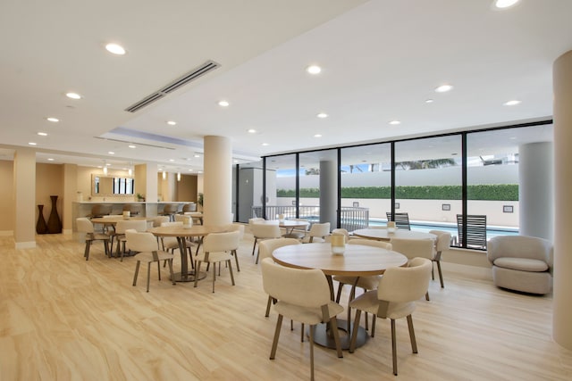 dining space featuring light wood-type flooring and floor to ceiling windows