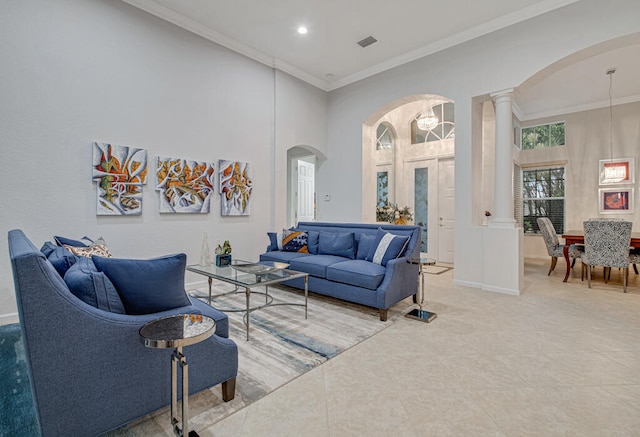 living room featuring a high ceiling, ornate columns, tile patterned floors, an inviting chandelier, and ornamental molding