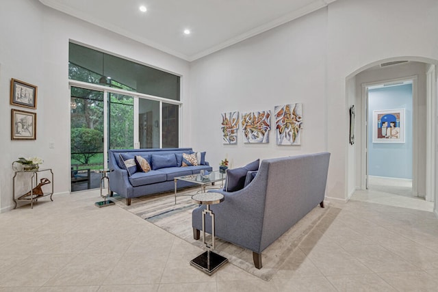 living room with tile patterned flooring, crown molding, and a high ceiling