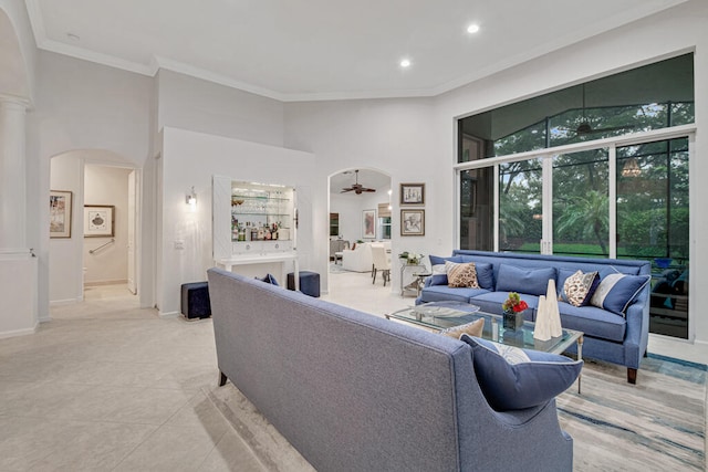 living room featuring ornamental molding, ceiling fan, a towering ceiling, and light tile patterned floors