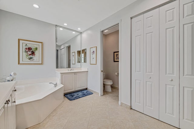 bathroom with tile patterned flooring, a tub, vanity, and toilet