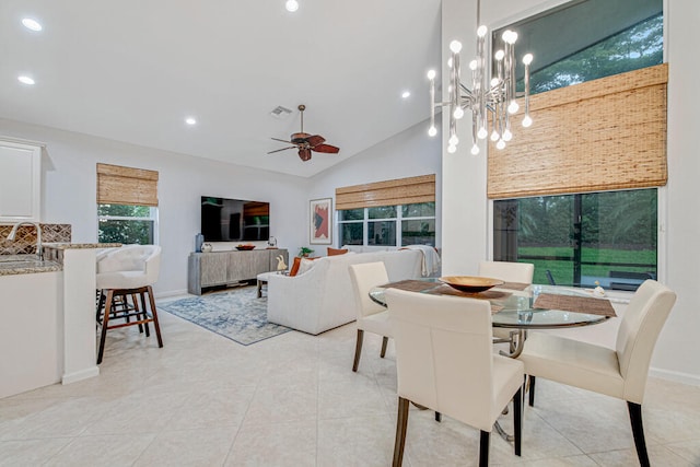 tiled dining area featuring ceiling fan with notable chandelier, high vaulted ceiling, and sink