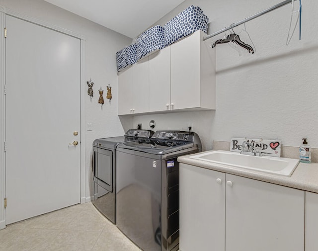 clothes washing area with light tile patterned floors, cabinets, sink, and washing machine and clothes dryer