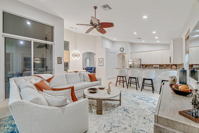 living room with ceiling fan with notable chandelier and high vaulted ceiling