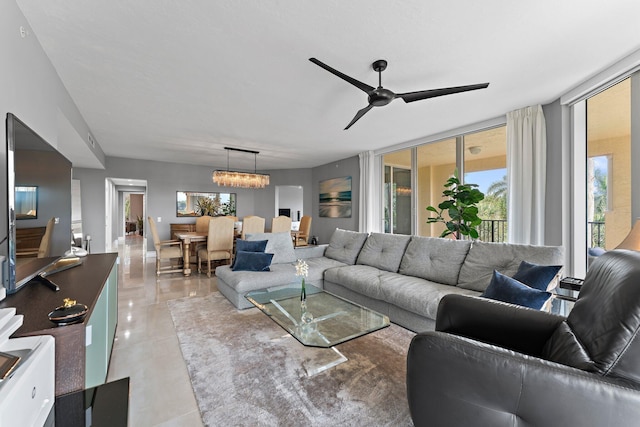 living room with light tile patterned floors and ceiling fan with notable chandelier