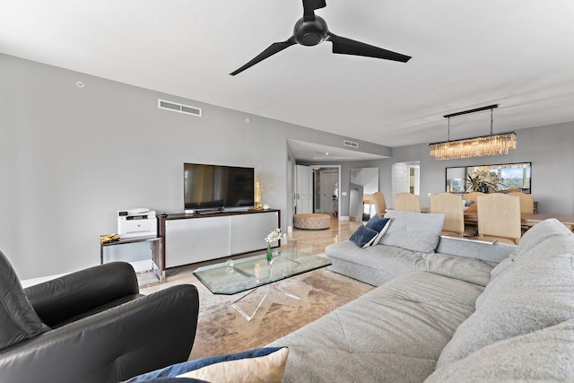 living room with light hardwood / wood-style floors and ceiling fan with notable chandelier