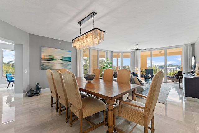 tiled dining area with ceiling fan with notable chandelier and floor to ceiling windows