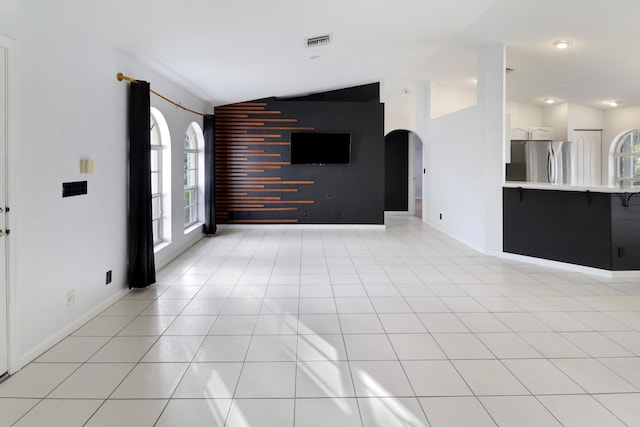 unfurnished living room with lofted ceiling and light tile patterned flooring