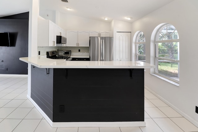 kitchen with white cabinetry, plenty of natural light, lofted ceiling, and appliances with stainless steel finishes