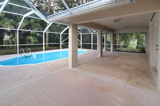 view of swimming pool with glass enclosure and a patio