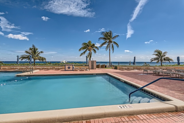 view of swimming pool featuring a water view and a patio