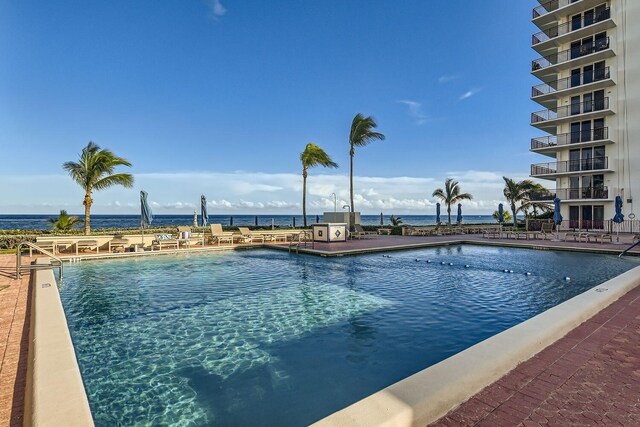 view of swimming pool with a lawn, a patio area, and a water view