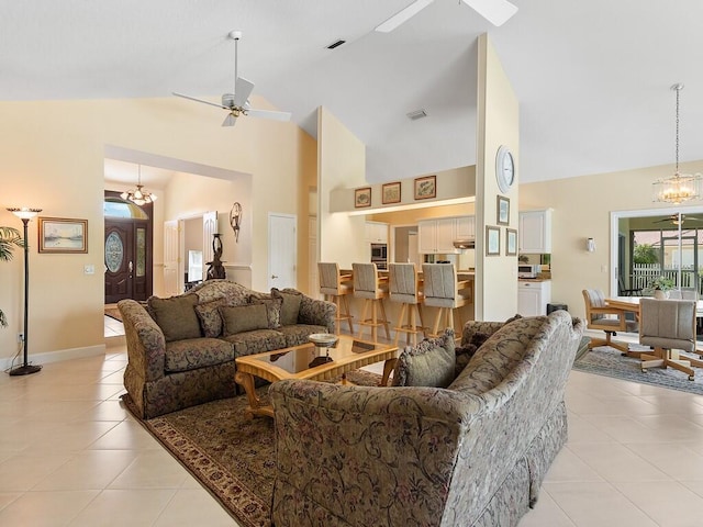 tiled living room featuring ceiling fan with notable chandelier and high vaulted ceiling