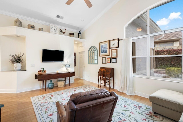 living room with light hardwood / wood-style floors, ornamental molding, and ceiling fan