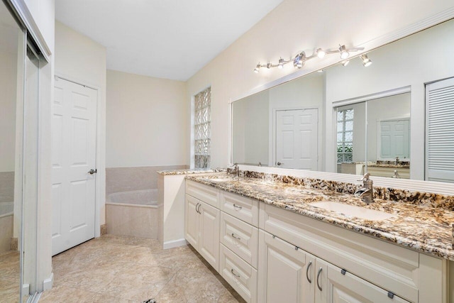 bathroom with tile patterned flooring, tiled tub, and vanity