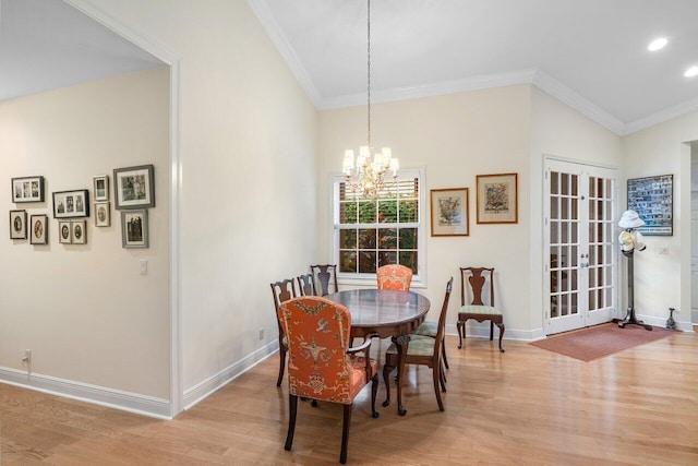 dining area with ornamental molding, an inviting chandelier, and light hardwood / wood-style floors