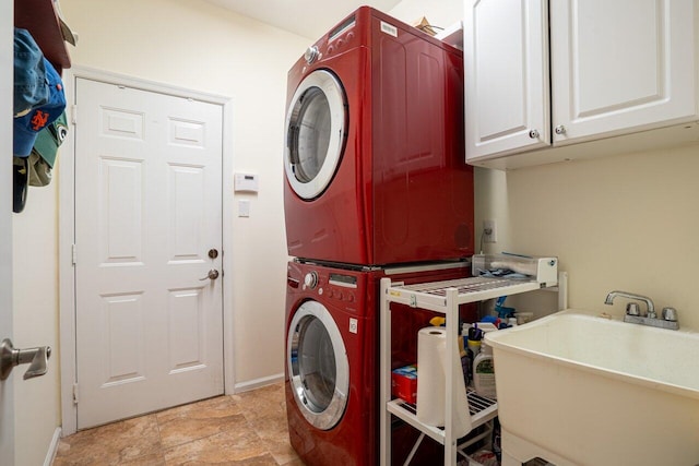 laundry room with cabinets, stacked washer / dryer, and sink