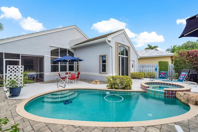 back of house with a sunroom, a patio area, and a pool with hot tub