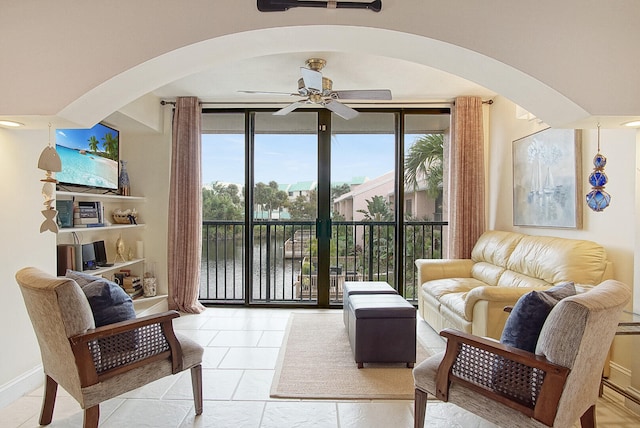 living room with a wall of windows, light tile patterned floors, and ceiling fan