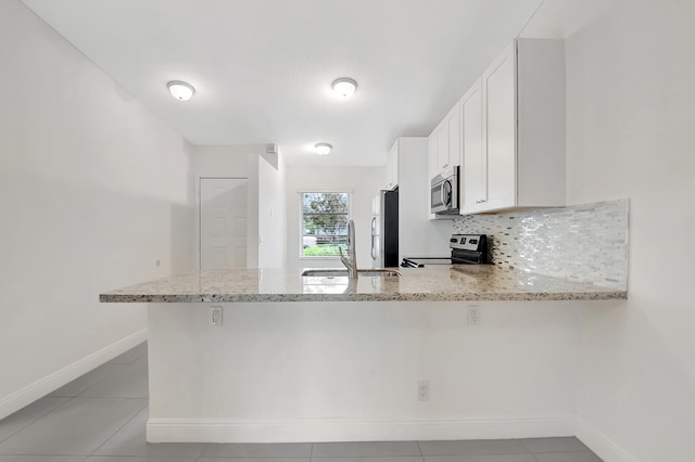 kitchen featuring sink, kitchen peninsula, white cabinetry, stainless steel appliances, and light stone countertops