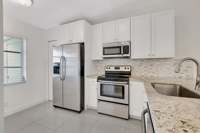 kitchen with tasteful backsplash, sink, light stone counters, stainless steel appliances, and white cabinets