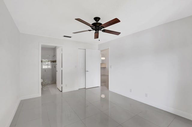 unfurnished bedroom with a closet, ceiling fan, light tile patterned floors, and ensuite bath