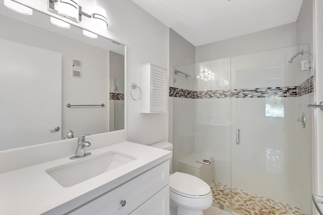 bathroom featuring vanity, a shower with shower door, and toilet