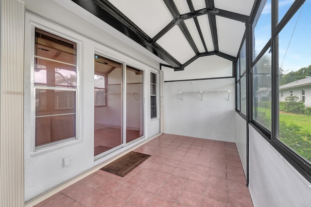 unfurnished sunroom featuring lofted ceiling with beams