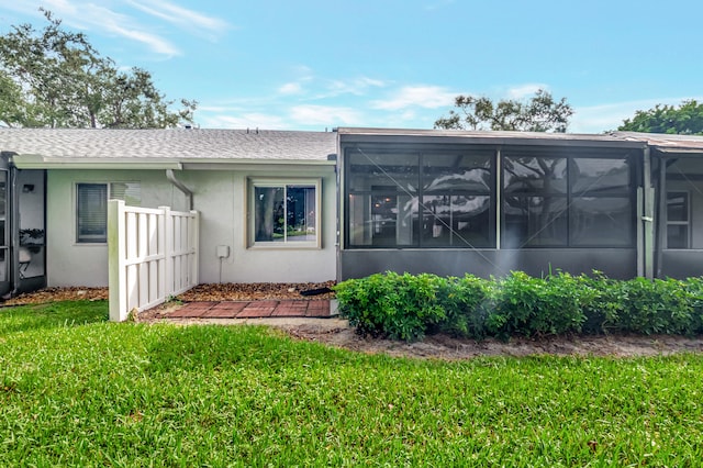 rear view of house featuring a sunroom and a yard