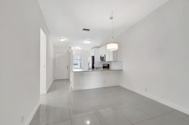 kitchen featuring light stone counters, white cabinets, light tile patterned flooring, pendant lighting, and kitchen peninsula