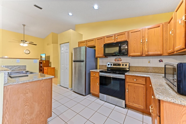 kitchen with ceiling fan, sink, light stone counters, vaulted ceiling, and appliances with stainless steel finishes