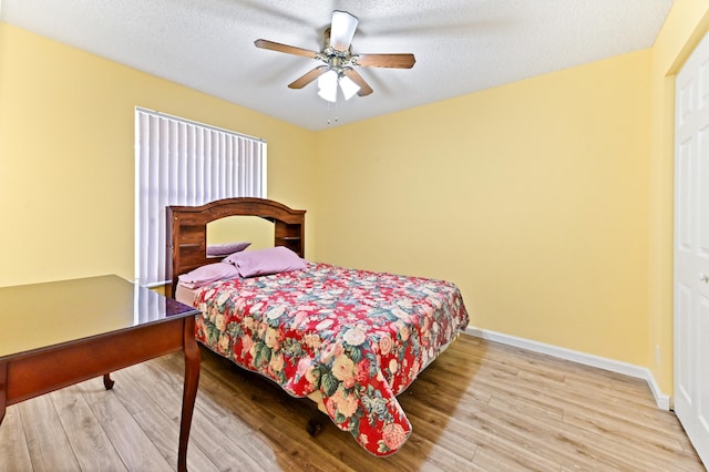 bedroom with ceiling fan, light hardwood / wood-style floors, and a textured ceiling