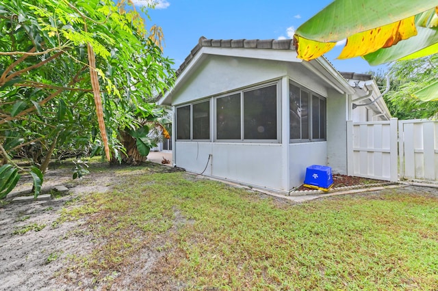 view of property exterior featuring a sunroom and a yard