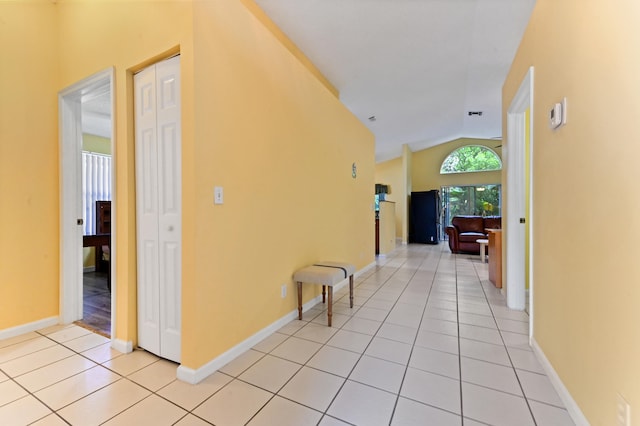 hall featuring light tile patterned floors and lofted ceiling