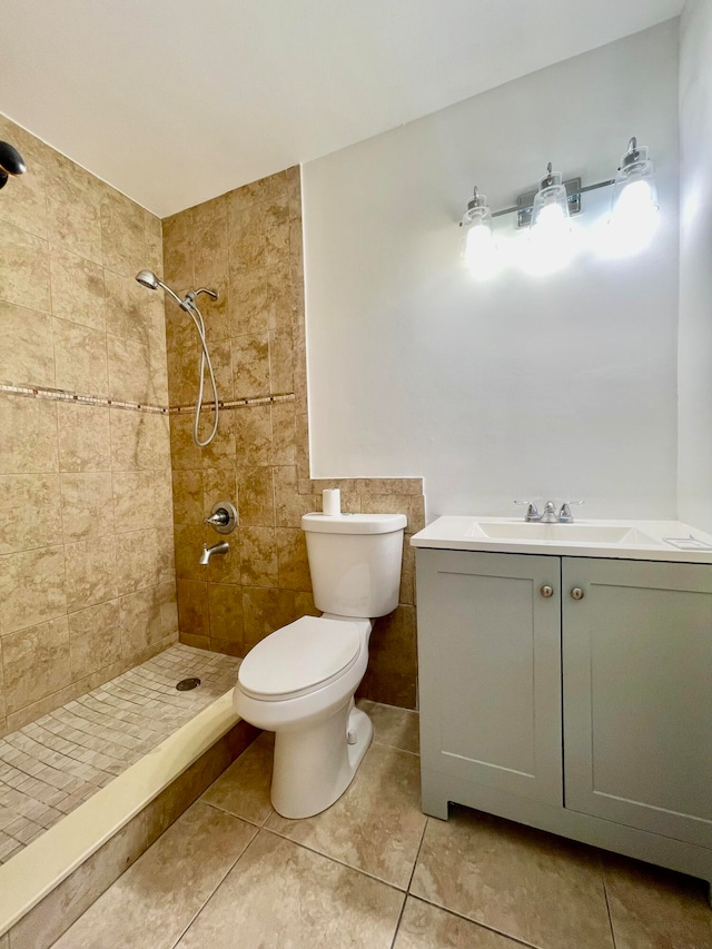 bathroom featuring a tile shower, tile patterned floors, vanity, and toilet