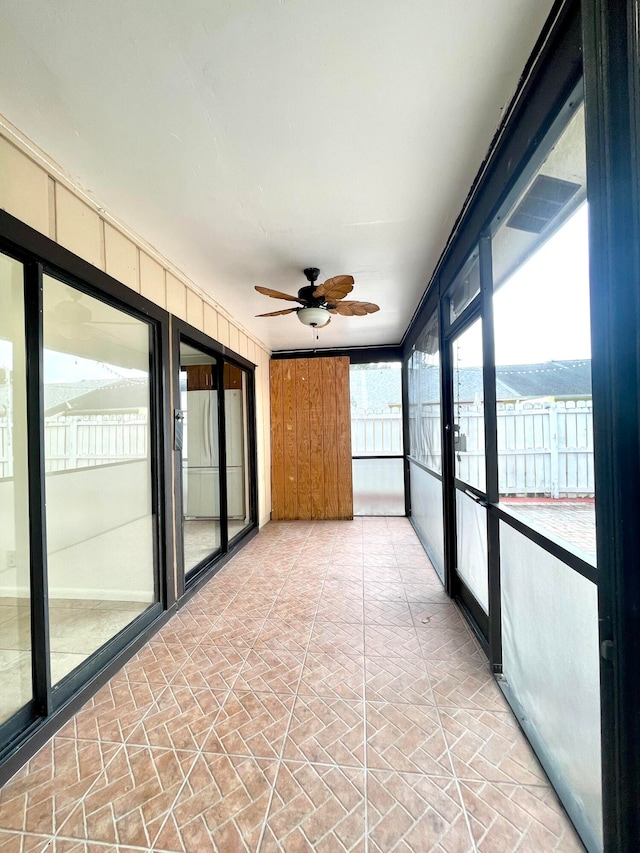 unfurnished sunroom featuring ceiling fan