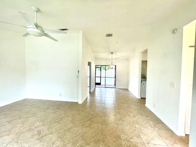 tiled empty room with ceiling fan with notable chandelier and washer / dryer