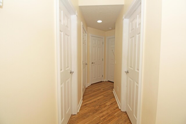 hallway with light hardwood / wood-style flooring and a textured ceiling