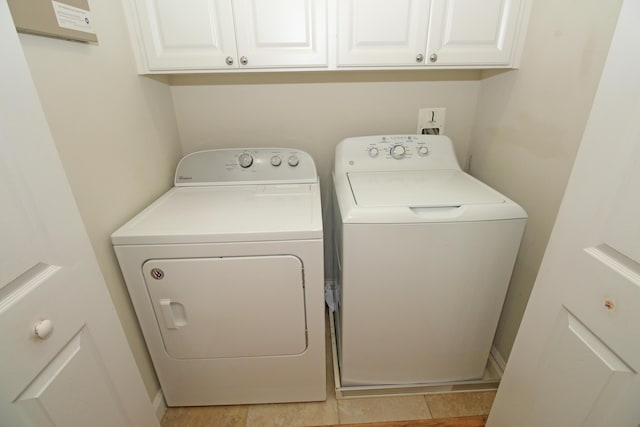 laundry area with separate washer and dryer, light tile patterned floors, and cabinets