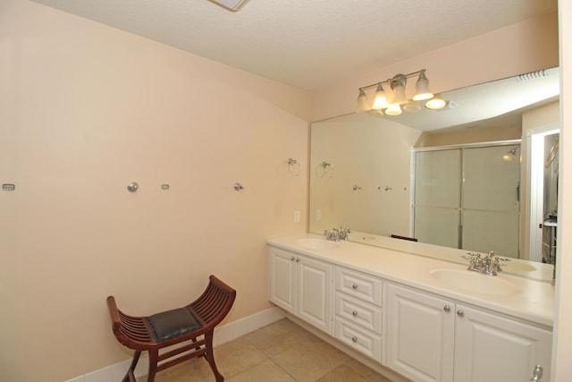 bathroom featuring tile patterned floors, a textured ceiling, vanity, and an enclosed shower